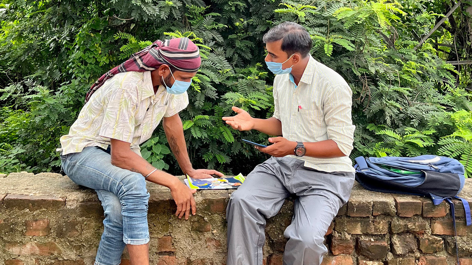 two men sit outside having a conversation.